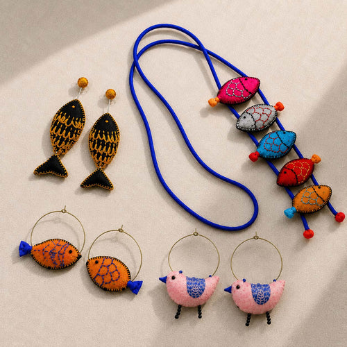 handcrafted fabric earrings inspired by fish and bird along with neckpiece with fish motifs laid out on a surface