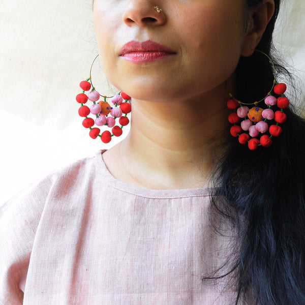 A woman wearing handcrafted red and yellow fabric Anokhi earrings 