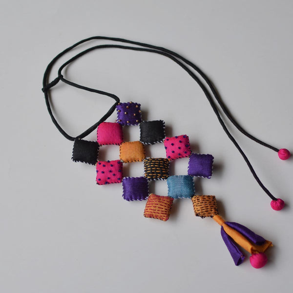 A multicolored geometric-patterned neckpiece with a tassel and adjustable black string.