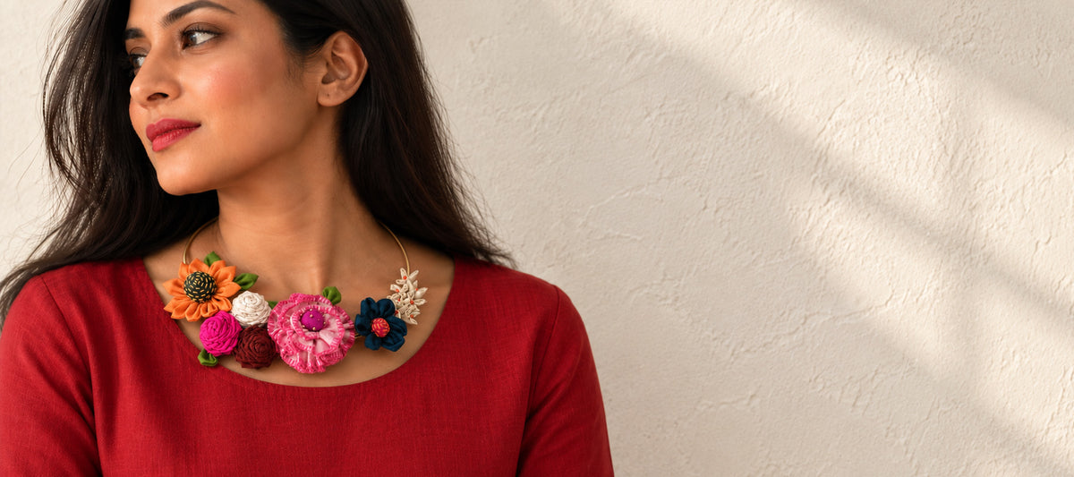 A woman wearing a Gul Hasli-floral handcrafted textile neckpiece featuring silk, fabric flowers in multicolor over a metal wire neckpiece.