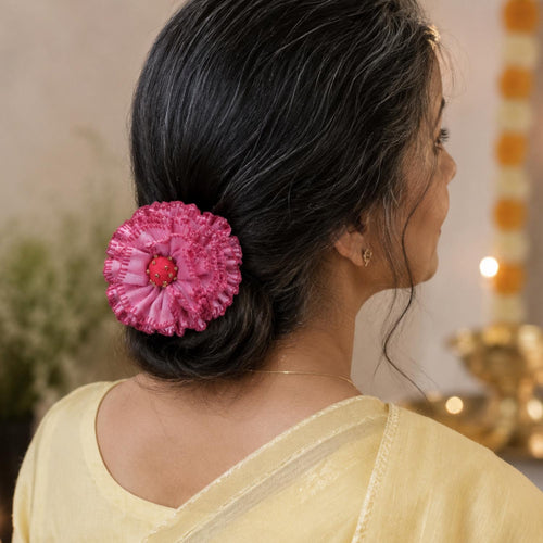 a woman with silver hair wears the handmade Phoolwanti baby pink fabric floral bun pin to secure her hair knot, in a festive dressup.