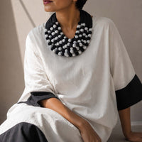 model wearing a statement handmade  Ratna necklace with black and white fabric beads.