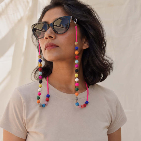 A woman wearing colorful beaded Sanchita specs string which has handmade multicolored fabric beads that can hang onto sunglasses.