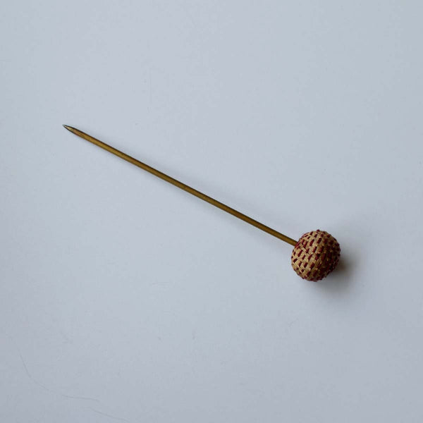 A fabric Handcrafted Sarala beige bun pin with a maroon hand embroidery kept on a white background.