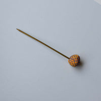 Flat lay of the Sarala bun stick, hair accessory in yellow fabric bead and blue hand embroidery.