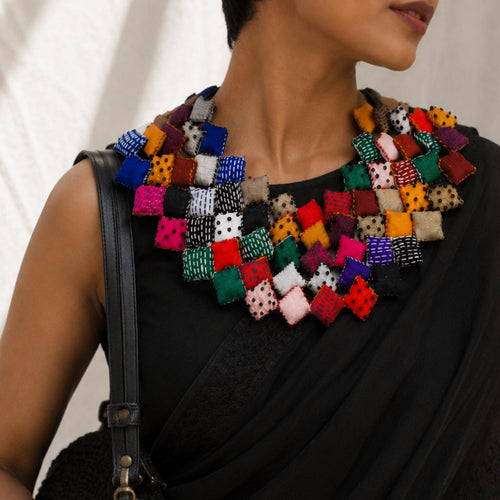 model wearing a large, colorful Tejaswini fabric bib necklace over a black saree