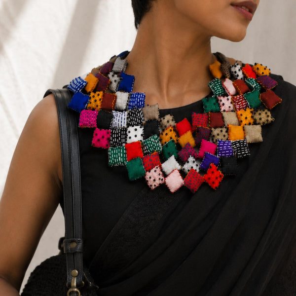 model wearing a large, colorful Tejaswini fabric bib necklace over a black saree