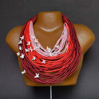 Statement neckpiece -Vanya fabric neckpiece with red, pink, and maroon strands, displayed on a mannequin bust.
