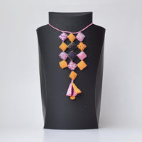 Ayanti handmade fabric neckpiece displayed on a black mannequin, featuring square pillows and a tassel.